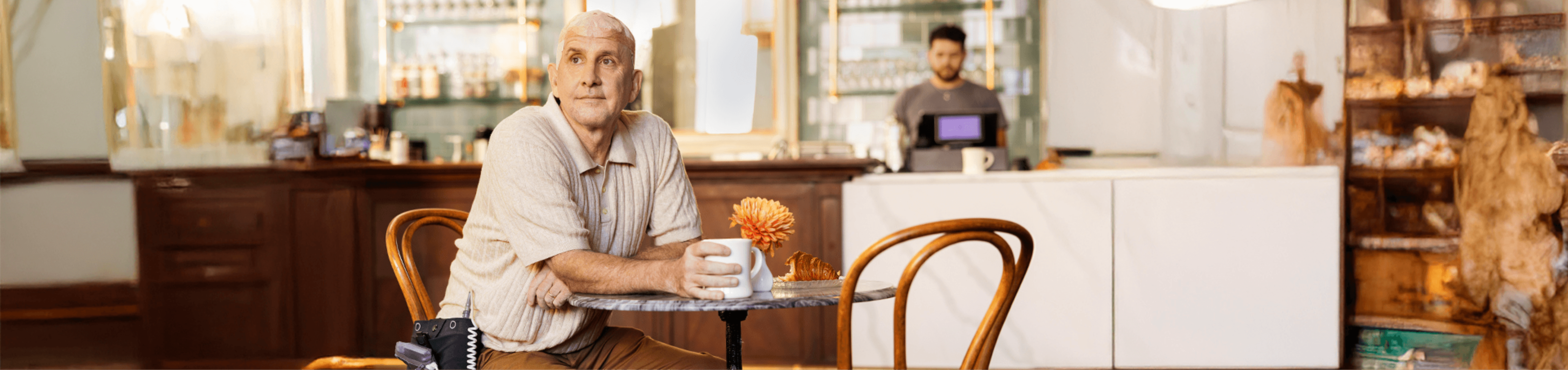 Sean sitting at a table in a café while using Optune Gio.