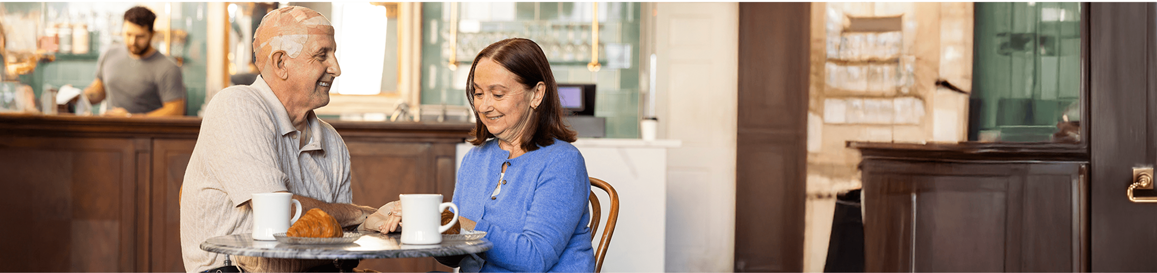 Sean and Rachel sitting together at a table in a café while Sean uses Optune Gio.