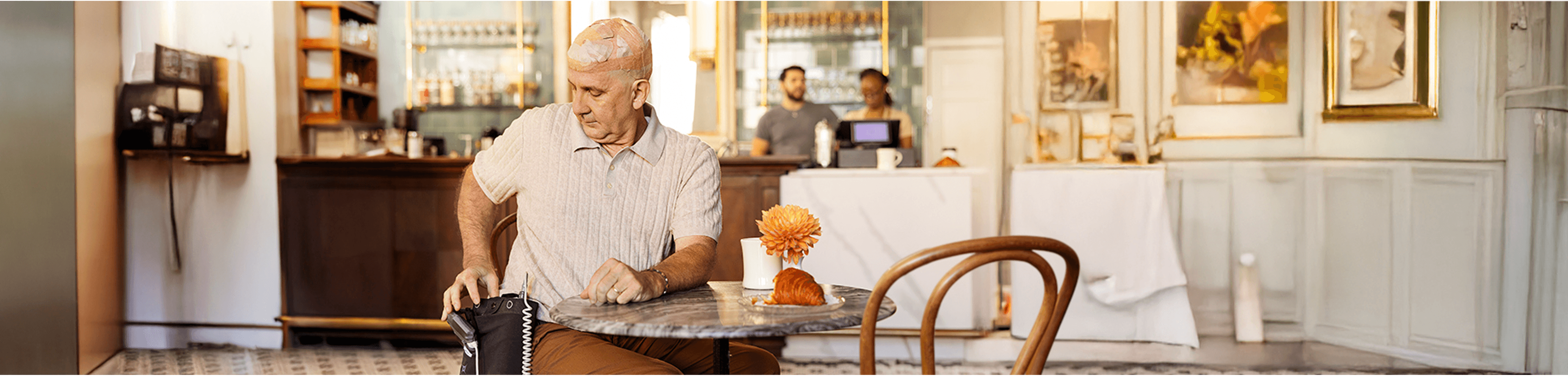 Sean sitting at a table in a café while using Optune Gio.